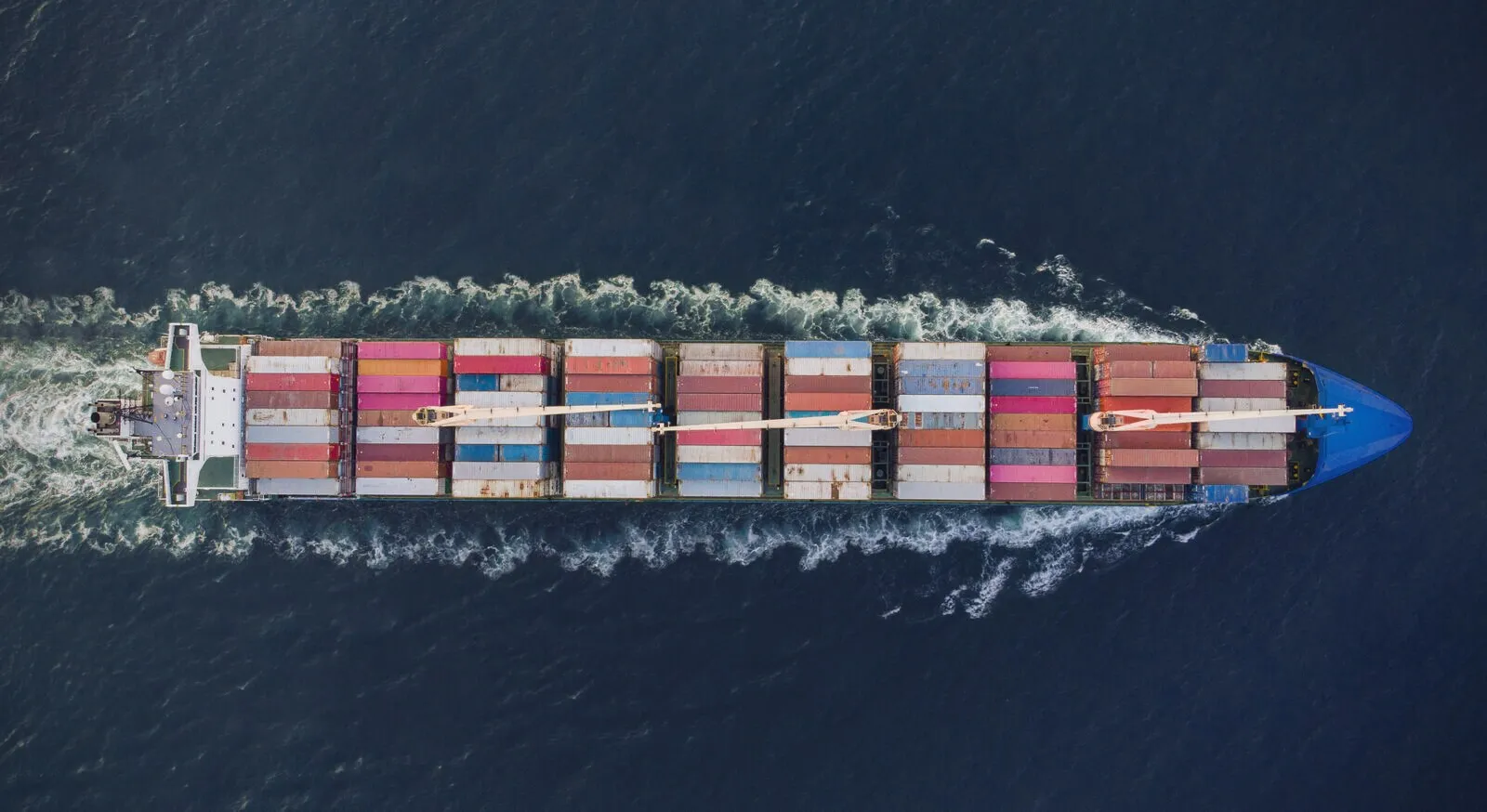 Containers stowed in rows on a vessel’s deck, open sea ahead